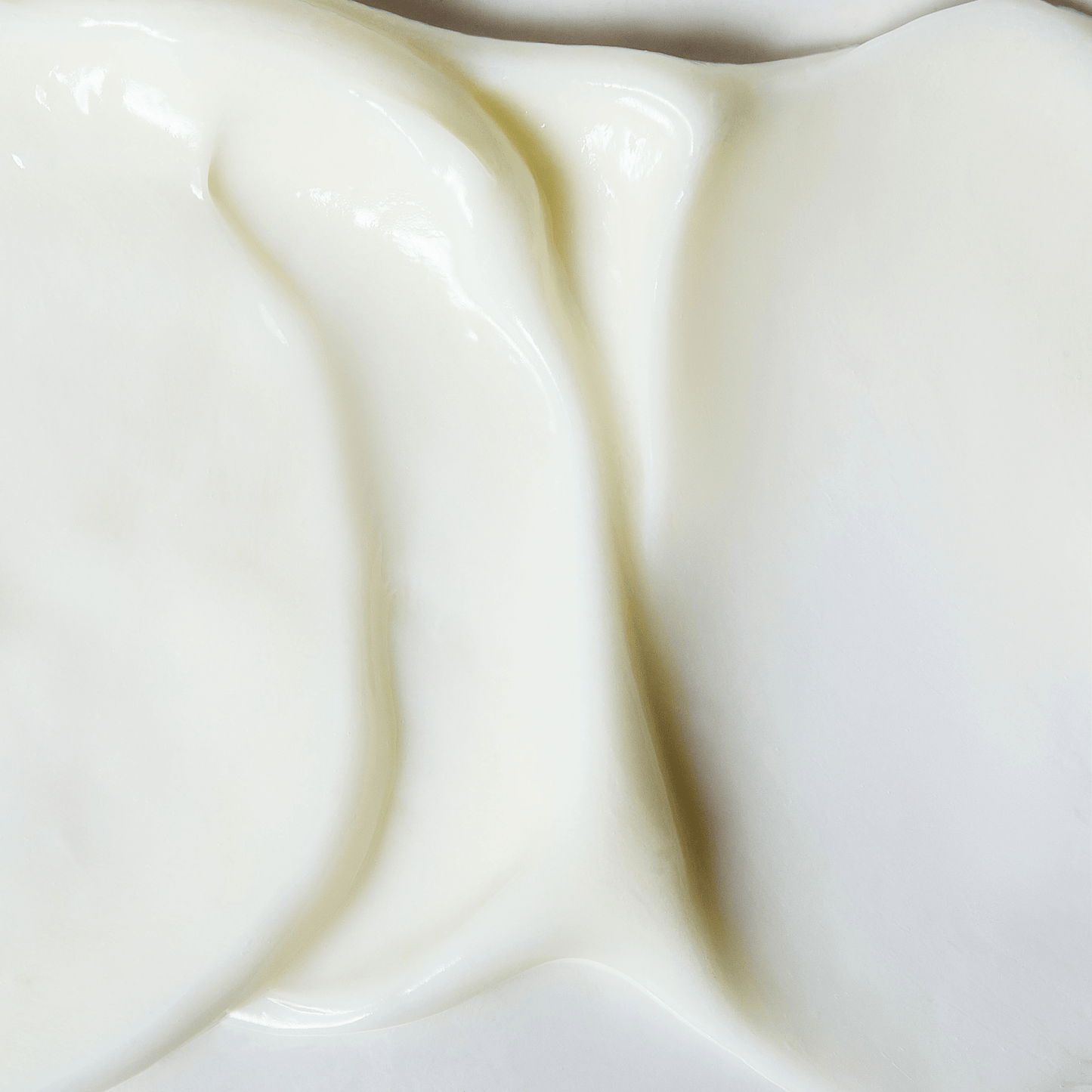 Close up texture of smooth, creamy white moisturizer spread evenly on a flat surface with a glossy finish