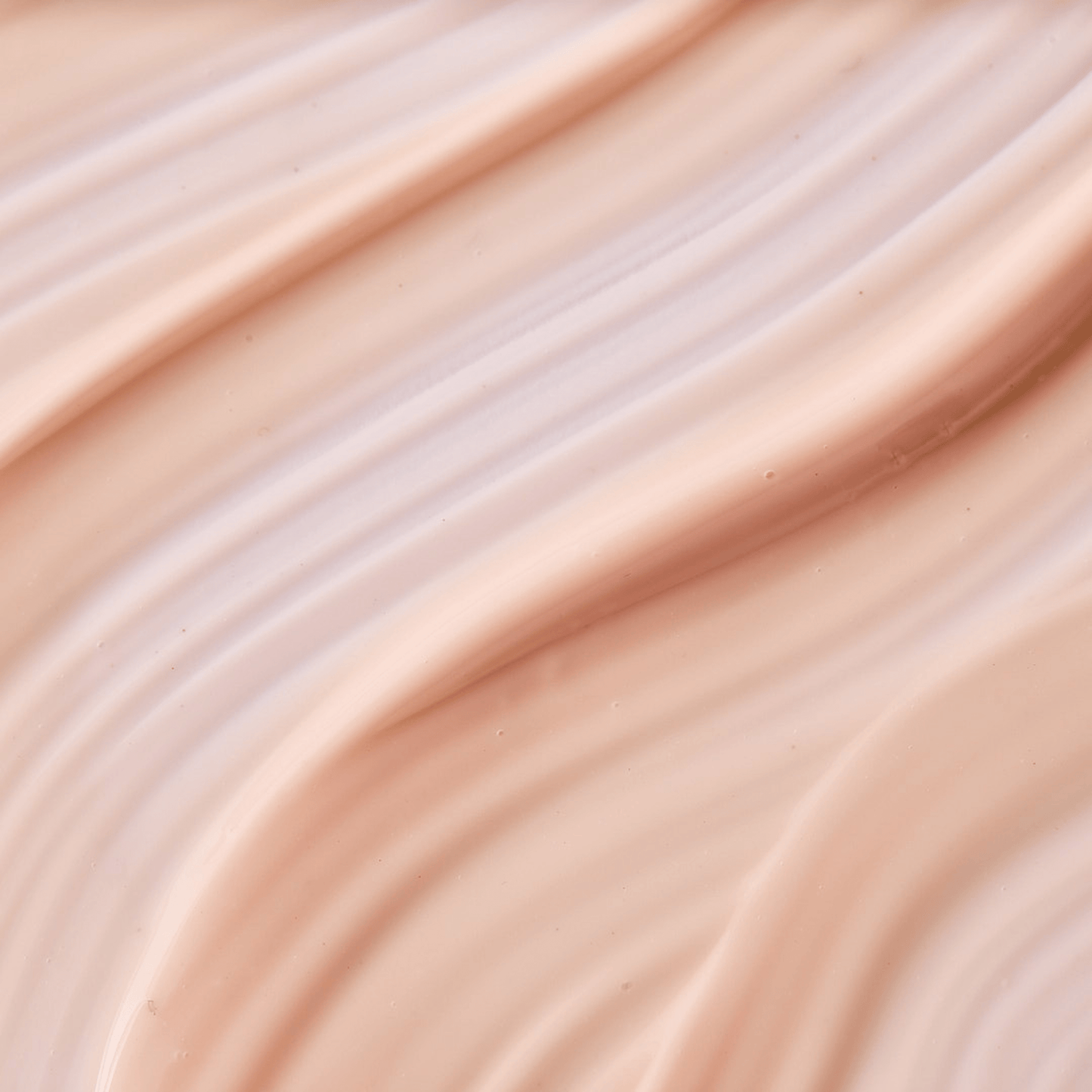 Close-up texture of a smooth, light beige cream with soft, wavy ridges and glossy finish.