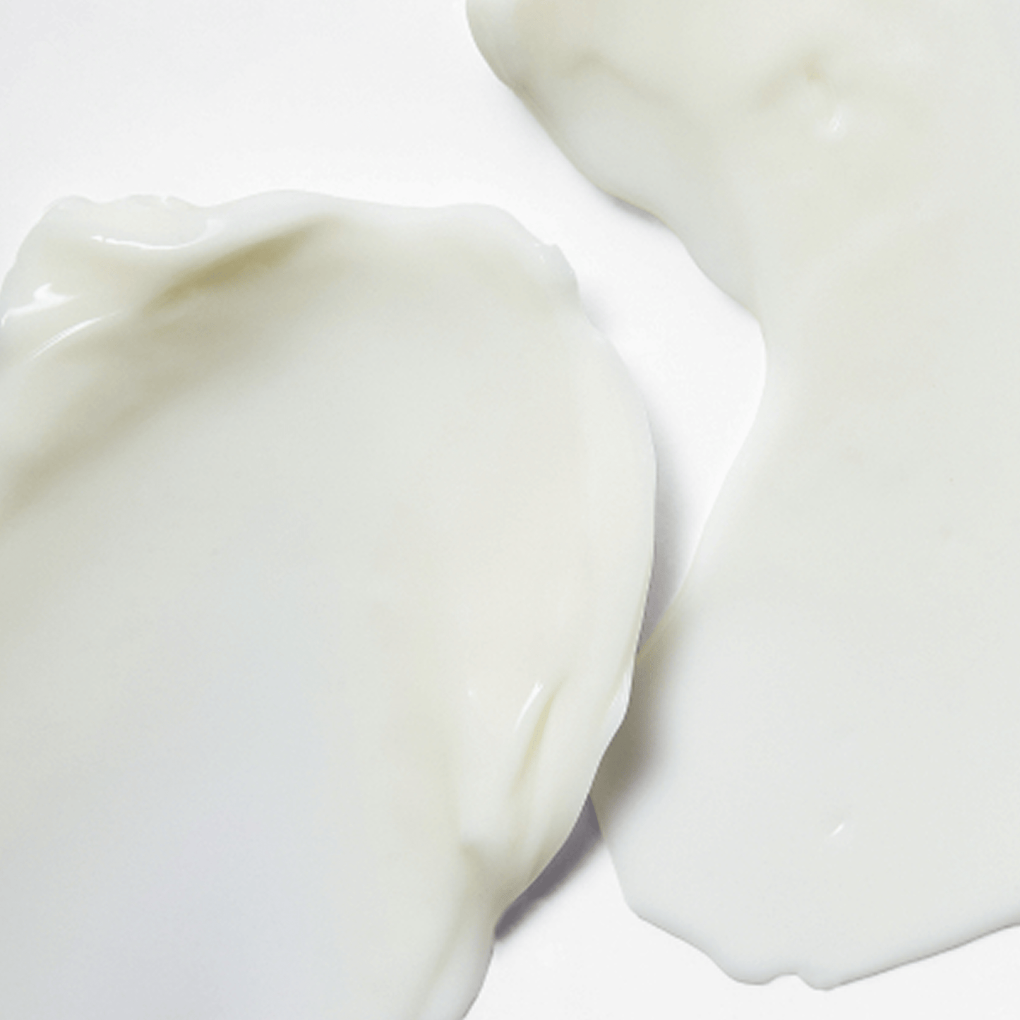Close-up of smooth, creamy white skincare product texture spread on a flat surface with a glossy finish.