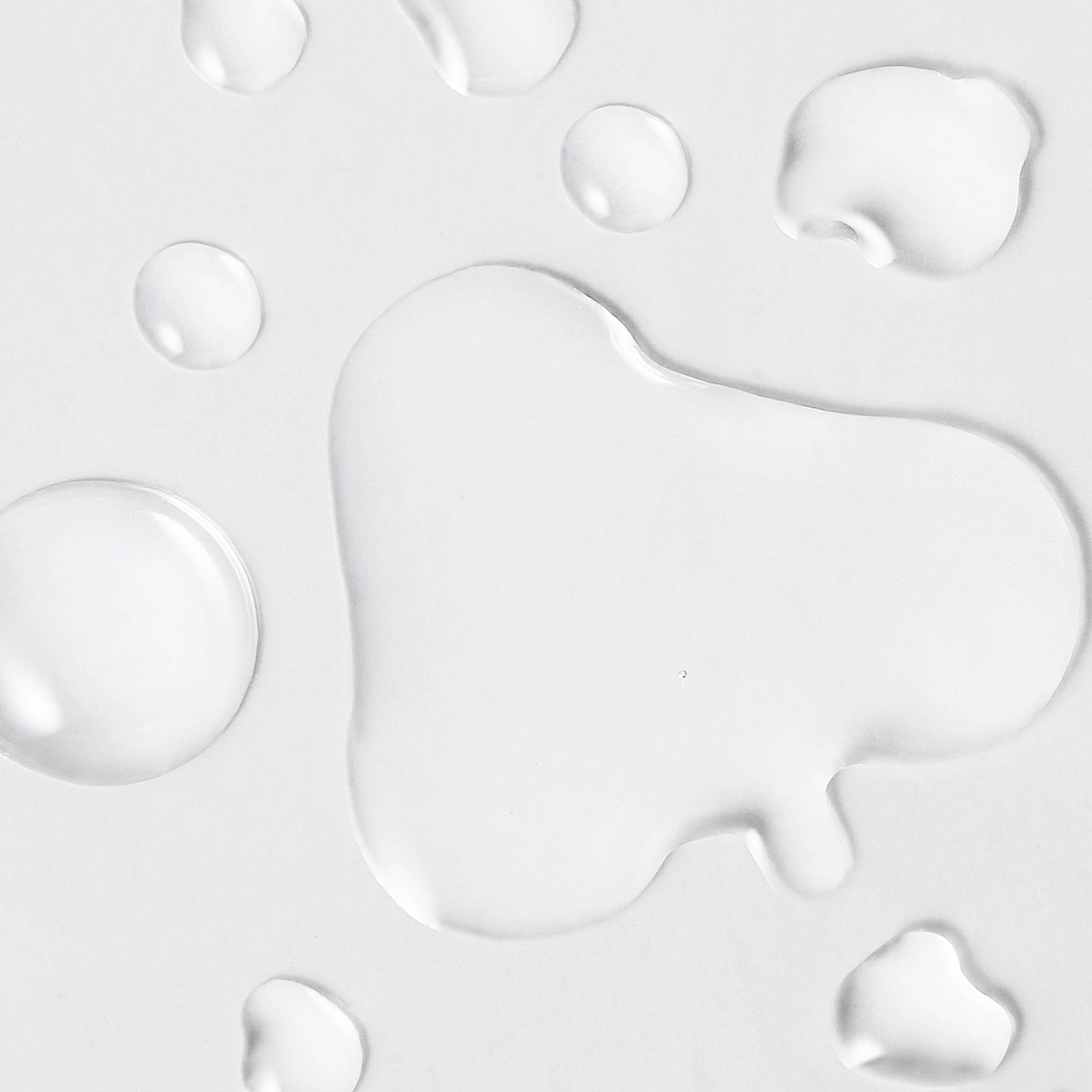 Close-up texture of the goPure Refine It! 2% BHA Liquid Exfoliant, showing clear liquid droplets spread across a smooth white surface. The image highlights the lightweight, watery consistency of the exfoliant formula.