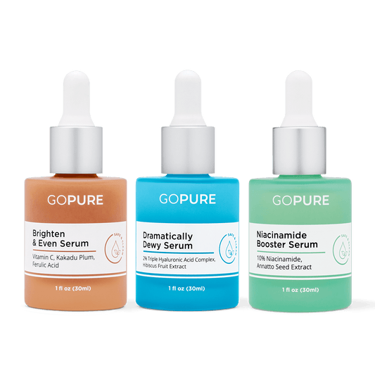 Image of three GoPure serum bottles: a peach-colored 'Brighten & Even Serum' with ingredients like Vitamin C and Ferulic Acid, a blue 'Dramatically Dewy Serum' with ingredients like Hyaluronic Acid, and a green 'Niacinamide Booster Serum' with ingredients like Niacinamide and Annatto Seed Extract.