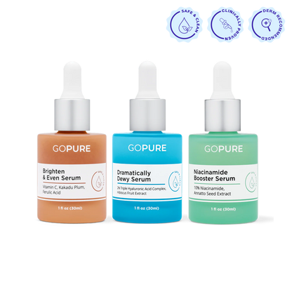 Three colorful goPure serum bottles with droppers shown side by side against a white background. From left to right: Brighten & Even Serum (orange, 1 fl oz/30 mL), Dramatically Dewy Serum (blue, 1 fl oz/30 mL), and Niacinamide Booster Serum (green, 1 fl oz/30 mL). Above them are three icons labeled Safe & Clean, Clinically Proven, and Derm Recommended.