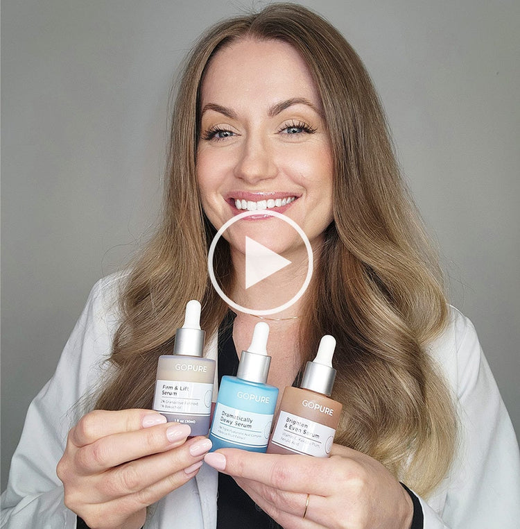Smiling woman with long blonde hair holding three GoPure skincare serums: Firm & Lift Serum, Dramatically Dewy Serum, and Brighten & Even Serum. A play button icon is overlaid on the image, indicating a video.