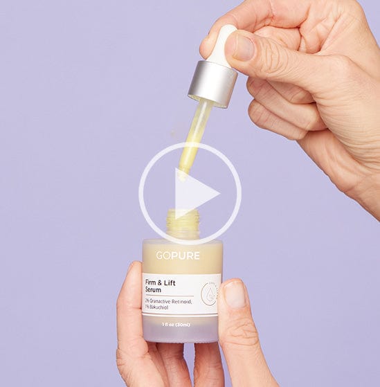 Hands holding a dropper and bottle of GoPure Firm & Lift Serum with 2% Granactive Retinoid and 1% Bakuchiol against a light purple background. A play button icon is overlaid, indicating a video.