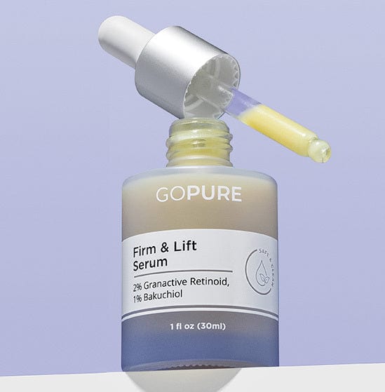 Bottle of GoPure Firm & Lift Serum with 2% Granactive Retinoid and 1% Bakuchiol. The dropper is filled with yellow serum and rests on the open bottle against a light purple background.