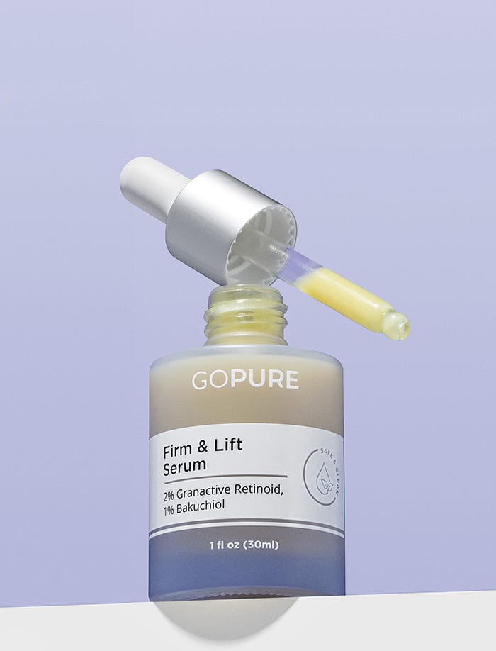 Bottle of GoPure Firm & Lift Serum with 2% Granactive Retinoid and 1% Bakuchiol. The dropper is filled with yellow serum and rests on the open bottle against a light purple background.